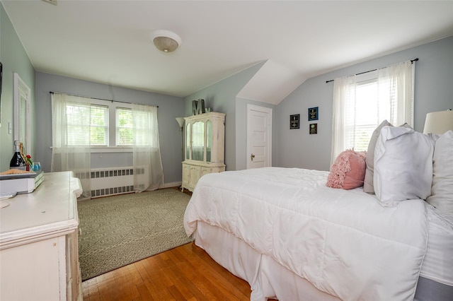 70 Loines Ave, Merrick, NY 11566 - bedroom featuring radiator, wood finished floors, and vaulted ceiling