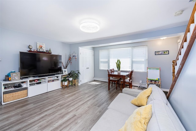 2226 124th St, College Point, NY 11356 - living room with wood finished floors, stairway, baseboards, and a baseboard heating unit