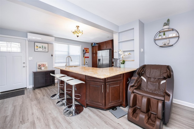 2226 124th St, College Point, NY 11356 - kitchen featuring stainless steel fridge with ice dispenser, light wood-type flooring, a breakfast bar, and light stone counters