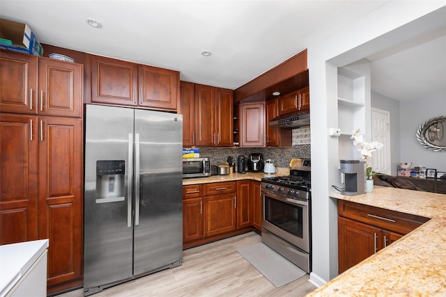 2226 124th St, College Point, NY 11356 - kitchen with stainless steel appliances, backsplash, under cabinet range hood, light wood-style flooring, and light stone counters