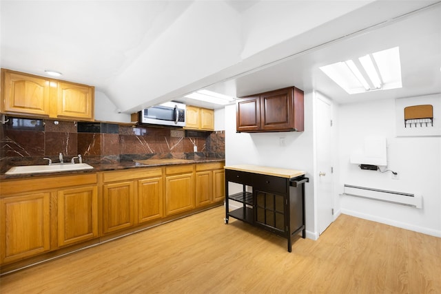 2226 124th St, College Point, NY 11356 - kitchen with baseboard heating, a sink, stainless steel microwave, light wood finished floors, and decorative backsplash