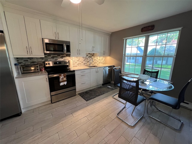 411A Weymouth Ct Unit 411A, Ridge, NY 11961 - kitchen with appliances with stainless steel finishes, a sink, light countertops, light wood-style flooring, and decorative backsplash