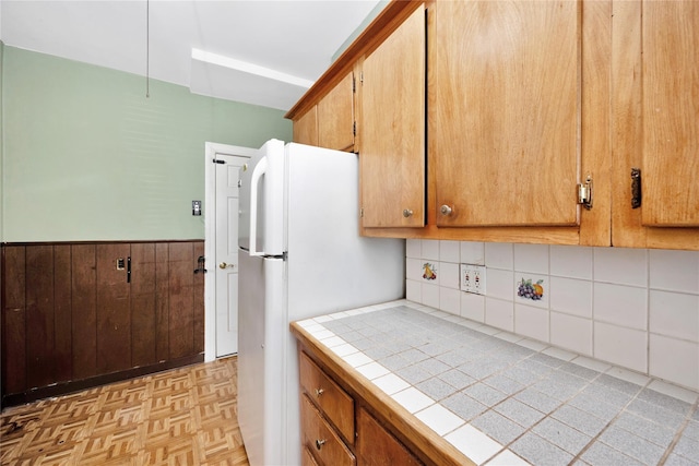 61-66 80th St, Middle Village, NY 11379 - kitchen featuring tile countertops, a wainscoted wall, freestanding refrigerator, brown cabinets, and tasteful backsplash