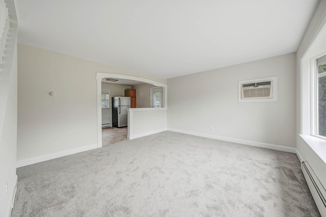 2251 Ocean Ave, Ronkonkoma, NY 11779 - unfurnished living room featuring a baseboard heating unit, light colored carpet, baseboards, arched walkways, and a baseboard radiator