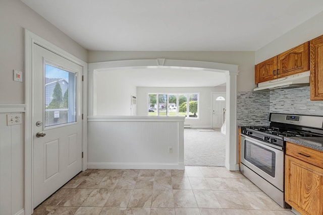 2251 Ocean Ave, Ronkonkoma, NY 11779 - kitchen with under cabinet range hood, gas stove, tasteful backsplash, brown cabinets, and a baseboard radiator
