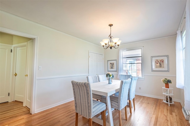 103 Woods Ave, Malverne, NY 11565 - dining space with a chandelier, light wood-style floors, crown molding, baseboards, and baseboard heating