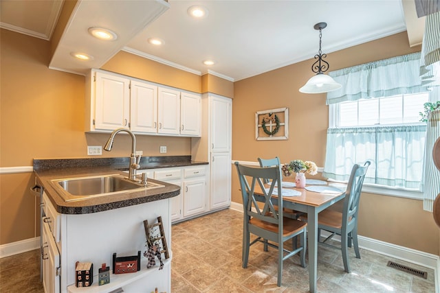 103 Woods Ave, Malverne, NY 11565 - kitchen featuring a sink, ornamental molding, dark countertops, white cabinets, and hanging light fixtures