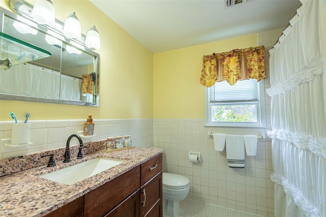 103 Woods Ave, Malverne, NY 11565 - bathroom with tile walls, tile patterned flooring, toilet, vanity, and a wainscoted wall