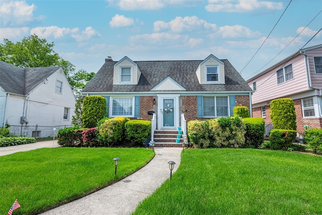 103 Woods Ave, Malverne, NY 11565 - cape cod house with brick siding, a front yard, a chimney, and a shingled roof