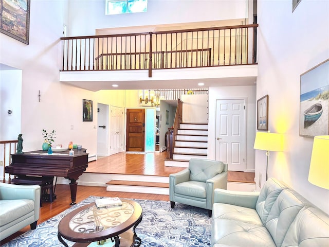 2 Greenwood Ct, Briarcliff Manor, NY 10510 - living room with a towering ceiling, wood finished floors, a baseboard heating unit, stairway, and baseboards