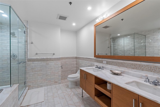 1 Renaissance Sq Unit 10H, White Plains, NY 10601 - bathroom featuring double vanity, tile walls, a shower stall, toilet, and recessed lighting