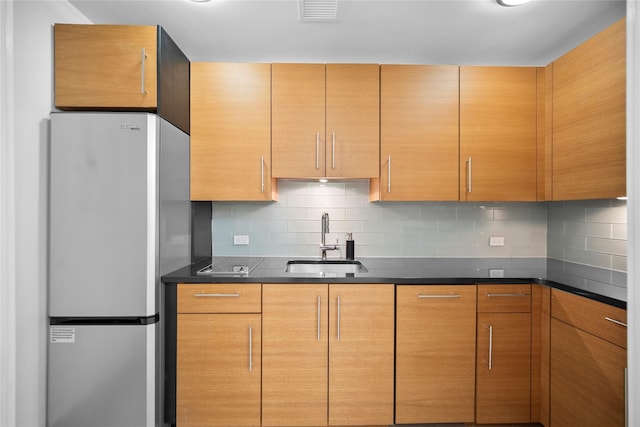 1 Renaissance Sq Unit 10B, White Plains, NY 10601 - kitchen with freestanding refrigerator, a sink, backsplash, and dark countertops