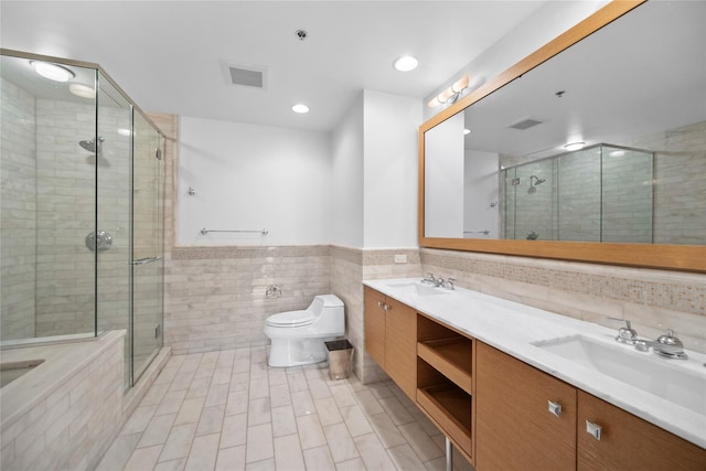 1 Renaissance Sq Unit 10B, White Plains, NY 10601 - bathroom with tile walls, double vanity, a stall shower, toilet, and tile patterned flooring