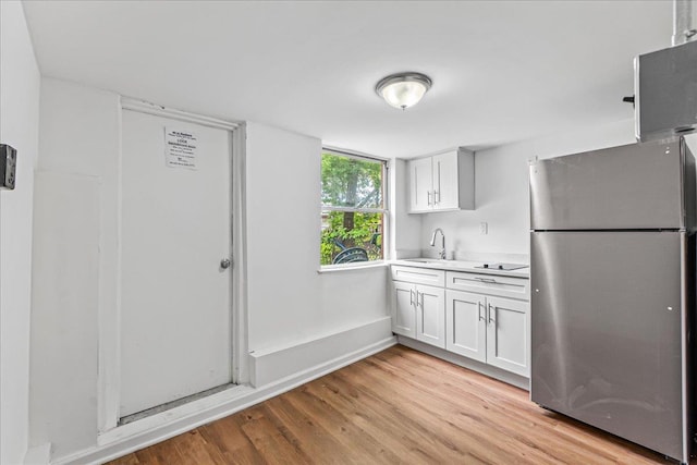 1049 E 219th St, Bronx, NY 10469 - kitchen with freestanding refrigerator, light countertops, light wood-style floors, a sink, and black electric cooktop