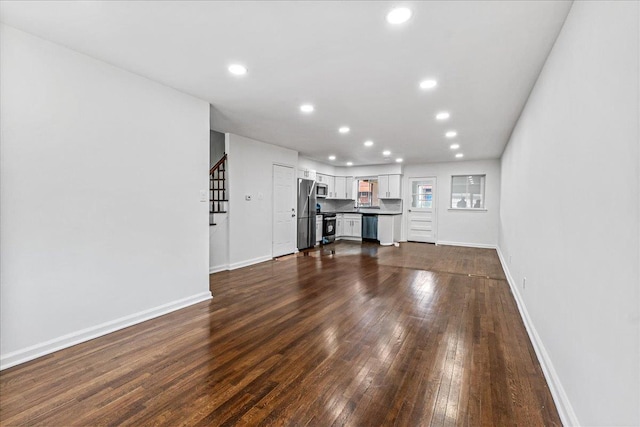 1049 E 219th St, Bronx, NY 10469 - unfurnished living room featuring dark wood-style floors, recessed lighting, baseboards, and stairs