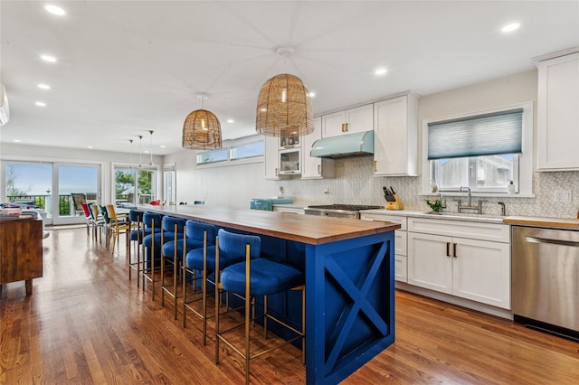 931A Oceanfront St, Long Beach, NY 11561 - kitchen featuring dishwasher, butcher block counters, under cabinet range hood, backsplash, and white cabinetry