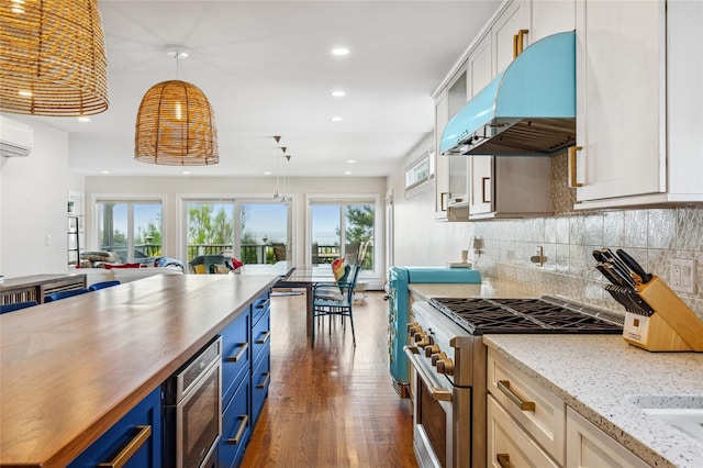 931A Oceanfront St, Long Beach, NY 11561 - kitchen with under cabinet range hood, blue cabinetry, appliances with stainless steel finishes, open floor plan, and dark wood finished floors