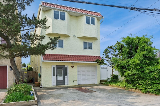 931A Oceanfront St, Long Beach, NY 11561 - view of front facade with a tiled roof, stucco siding, an attached garage, and concrete driveway