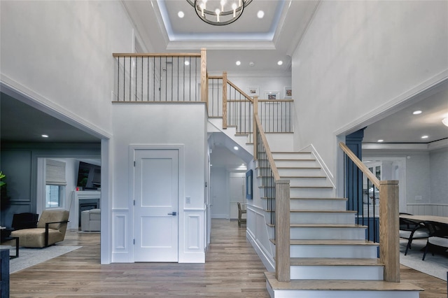 9 Wyndham Way, Port Washington, NY 11050 - stairway featuring a high ceiling, ornamental molding, a chandelier, wood finished floors, and a decorative wall