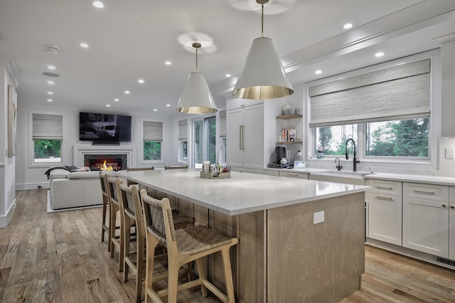9 Wyndham Way, Port Washington, NY 11050 - kitchen featuring a kitchen island, open floor plan, a sink, light stone counters, and recessed lighting