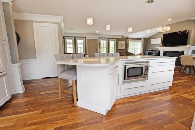 213 Glenwood Ln, Port Jefferson, NY 11777 - kitchen with stainless steel microwave, open floor plan, light countertops, wood finished floors, and ornamental molding