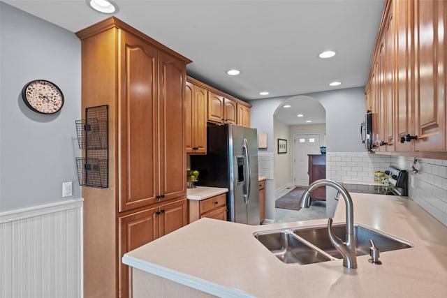 5005 John Hancock Ct Unit 100, New Windsor, NY 12553 - kitchen featuring appliances with stainless steel finishes, a sink, arched walkways, backsplash, and light countertops
