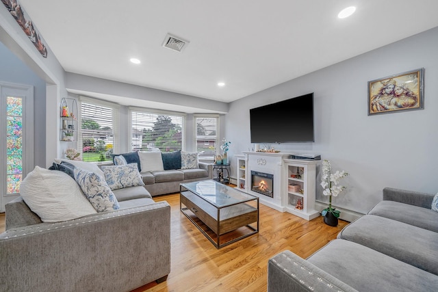 130 W 7th St, Deer Park, NY 11729 - living area featuring light wood finished floors, recessed lighting, a glass covered fireplace, a baseboard radiator, and baseboards