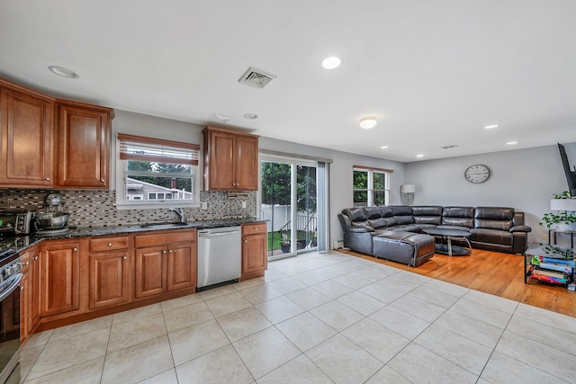 130 W 7th St, Deer Park, NY 11729 - kitchen featuring stainless steel appliances, a sink, open floor plan, decorative backsplash, and light tile patterned floors