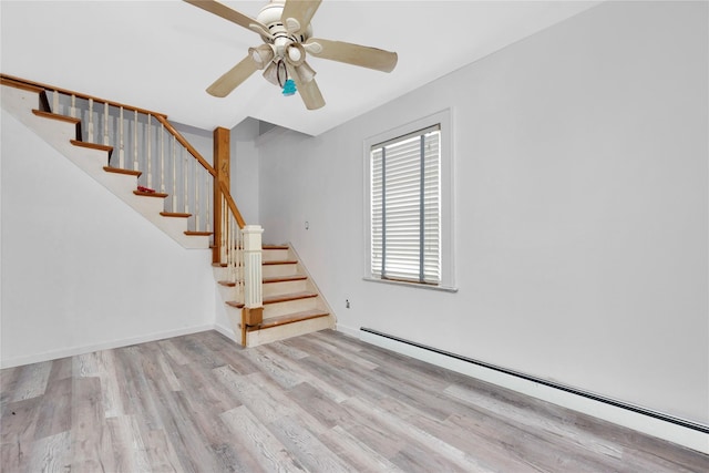 3680 Naomi St, Seaford, NY 11783 - unfurnished living room featuring baseboard heating, wood finished floors, stairs, ceiling fan, and baseboards