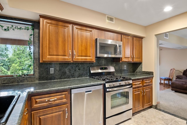 13 Evans Ave, Albertson, NY 11507 - kitchen featuring appliances with stainless steel finishes, dark countertops, brown cabinets, tasteful backsplash, and recessed lighting