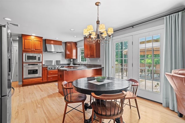 17 Jackson Ln, Campbell Hall, NY 10916 - kitchen with stainless steel appliances, wall chimney range hood, light wood-style floors, a chandelier, and a peninsula