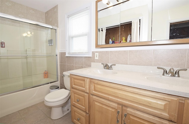 32 Shore Dr, Mastic Beach, NY 11951 - full bath featuring toilet, double vanity, tile walls, tile patterned flooring, and combined bath / shower with glass door