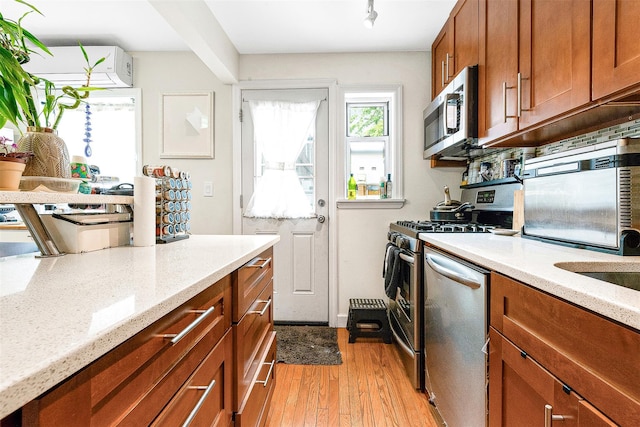 110-25 64th Rd Unit 10, Forest Hills, NY 11375 - kitchen featuring appliances with stainless steel finishes, light wood-style floors, brown cabinets, and light stone counters