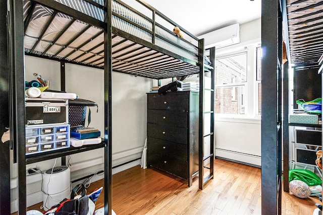 110-25 64th Rd Unit 10, Forest Hills, NY 11375 - bedroom featuring wood finished floors, a baseboard heating unit, and an AC wall unit