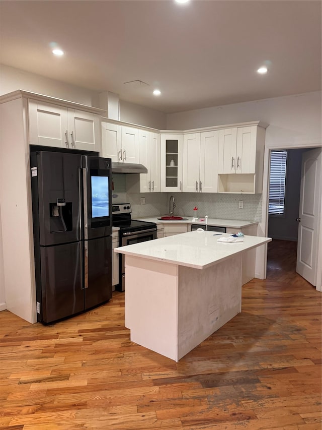 2311 Cortelyou Rd, Brooklyn, NY 11226 - kitchen with black fridge, a sink, under cabinet range hood, light countertops, and white cabinetry