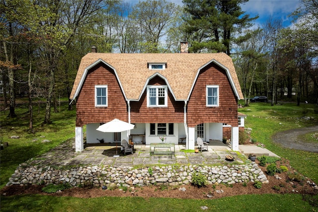57 Dellenbaugh Rd, Cragsmoor, NY 12566 - back of property featuring a patio, a gambrel roof, a chimney, and roof with shingles