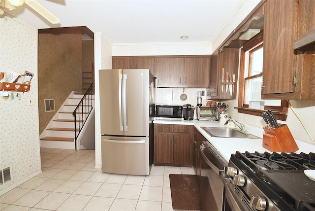 2 Walnut Dr, Syosset, NY 11791 - kitchen featuring stainless steel appliances, wallpapered walls, a sink, light countertops, and light tile patterned flooring