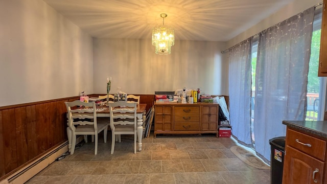 23 Kingsland Ave, Shirley, NY 11967 - dining room with a chandelier, healthy amount of natural light, baseboard heating, a wainscoted wall, and stone finish floors