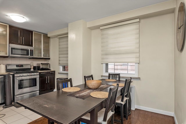 61-15 97th St Unit 6A, Rego Park, NY 11374 - kitchen featuring appliances with stainless steel finishes, dark brown cabinets, baseboards, glass insert cabinets, and decorative backsplash
