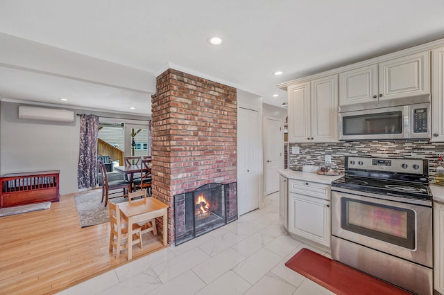 49 Rainbow Ln, Levittown, NY 11756 - kitchen featuring appliances with stainless steel finishes, a wall unit AC, light marble finish flooring, light countertops, and recessed lighting