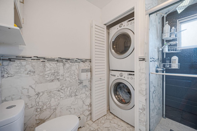 49 Rainbow Ln, Levittown, NY 11756 - bathroom with stacked washer and clothes dryer, toilet, tile walls, marble finish floors, and wainscoting