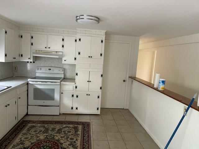2975 Rte 9, Cold Spring, NY 10516 - kitchen with white electric range oven, under cabinet range hood, white cabinets, and light tile patterned flooring