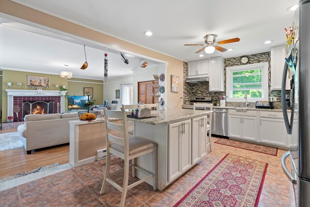 2975 Rte 9, Cold Spring, NY 10516 - kitchen featuring appliances with stainless steel finishes, crown molding, under cabinet range hood, a kitchen bar, and white cabinets