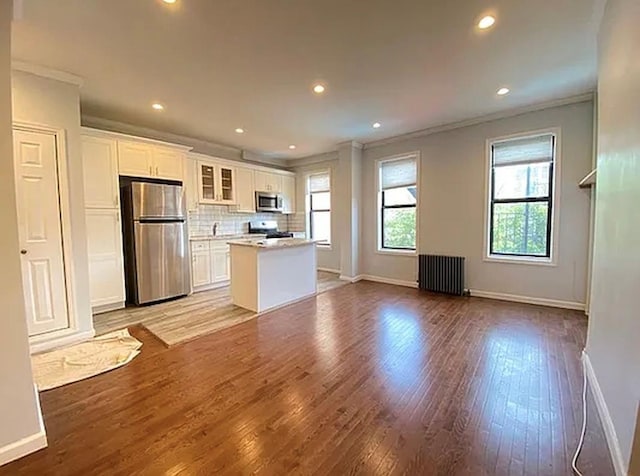 5840 Catalpa Ave, Ridgewood, NY 11385 - kitchen featuring appliances with stainless steel finishes, radiator heating unit, crown molding, baseboards, and a center island
