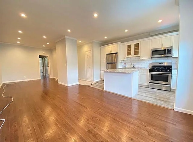 5840 Catalpa Ave, Ridgewood, NY 11385 - kitchen featuring stainless steel appliances, baseboards, a kitchen island, white cabinetry, and light wood finished floors