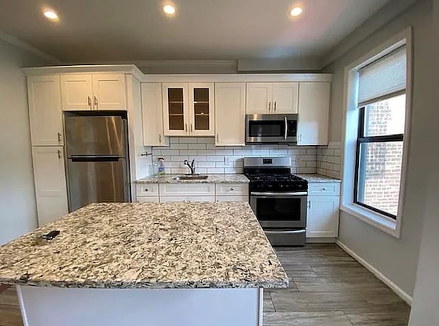 5840 Catalpa Ave, Ridgewood, NY 11385 - kitchen featuring stainless steel appliances, a sink, white cabinetry, a center island, and backsplash