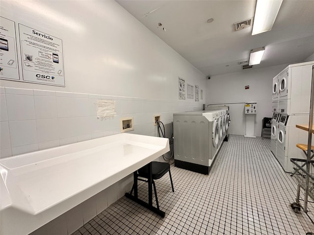 35-38 Junction Blvd Unit 6C, Jackson Heights, NY 11368 - shared laundry featuring stacked washing machine and dryer, washer and clothes dryer, light tile patterned floors, a wainscoted wall, and tile walls