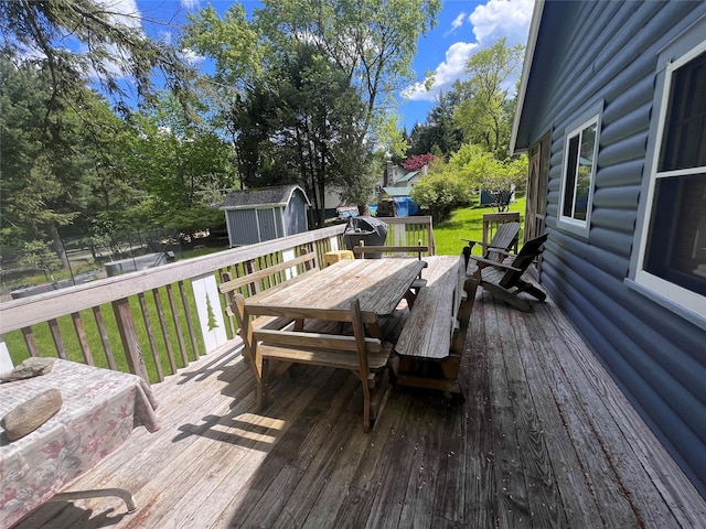 23 N Seminole Trl, Bethel, NY 12778 - wooden deck featuring outdoor dining area, a storage unit, a lawn, and view of scattered trees