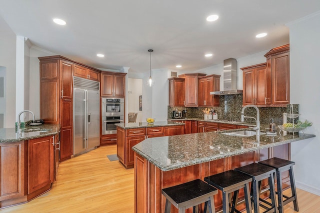 57 Varsity Blvd, East Setauket, NY 11733 - kitchen with stainless steel appliances, wall chimney exhaust hood, a peninsula, a sink, and crown molding