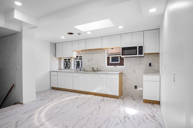 7 Lake St, Monticello, NY 12701 - kitchen featuring white microwave, a skylight, white cabinets, light marble finish floors, and wall oven